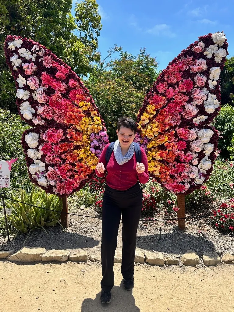 Tasha, standing in front of a flower butterfly wings display
